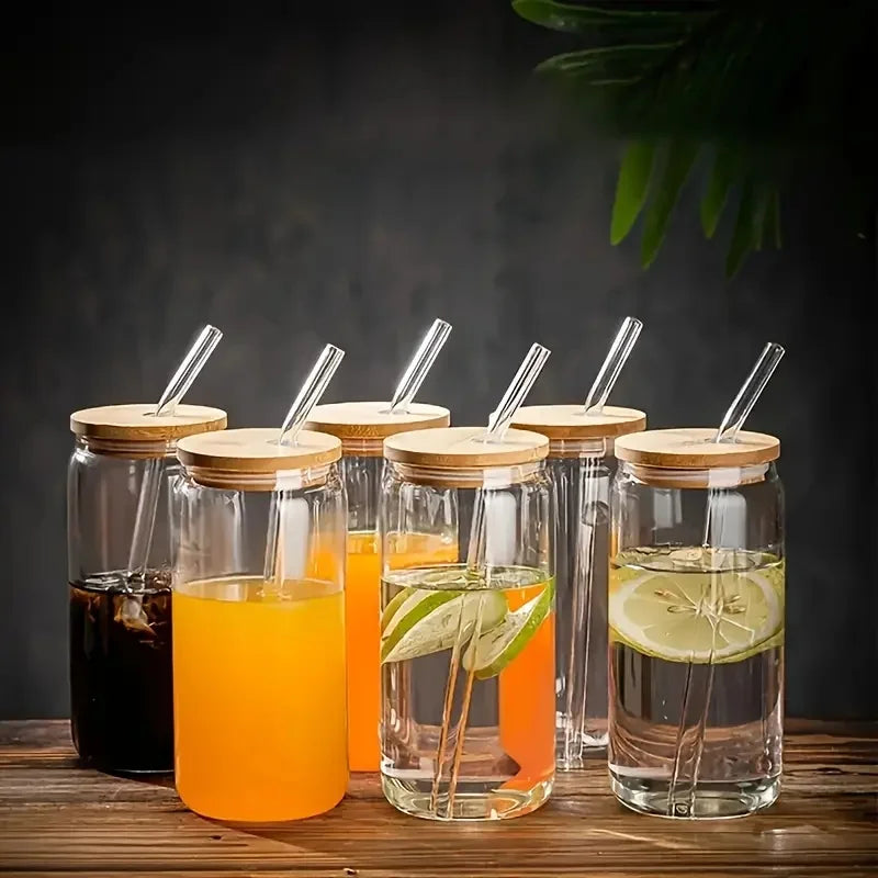 Set of glass jars with wooden lids and straws, containing different beverages on a wooden surface.