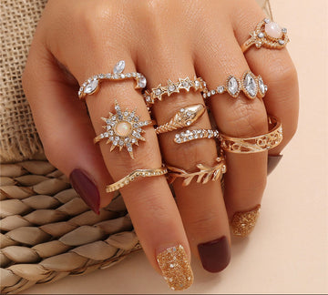 Hand wearing multiple gold and silver rings with a textured beige background