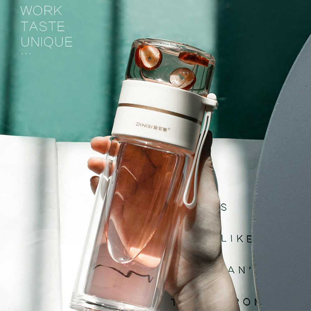 Clear water bottle with white base and pink interior held by a hand against a blurred background