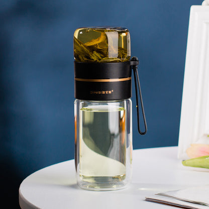 Clear glass bottle with black lid and handle on a white surface with blue background
