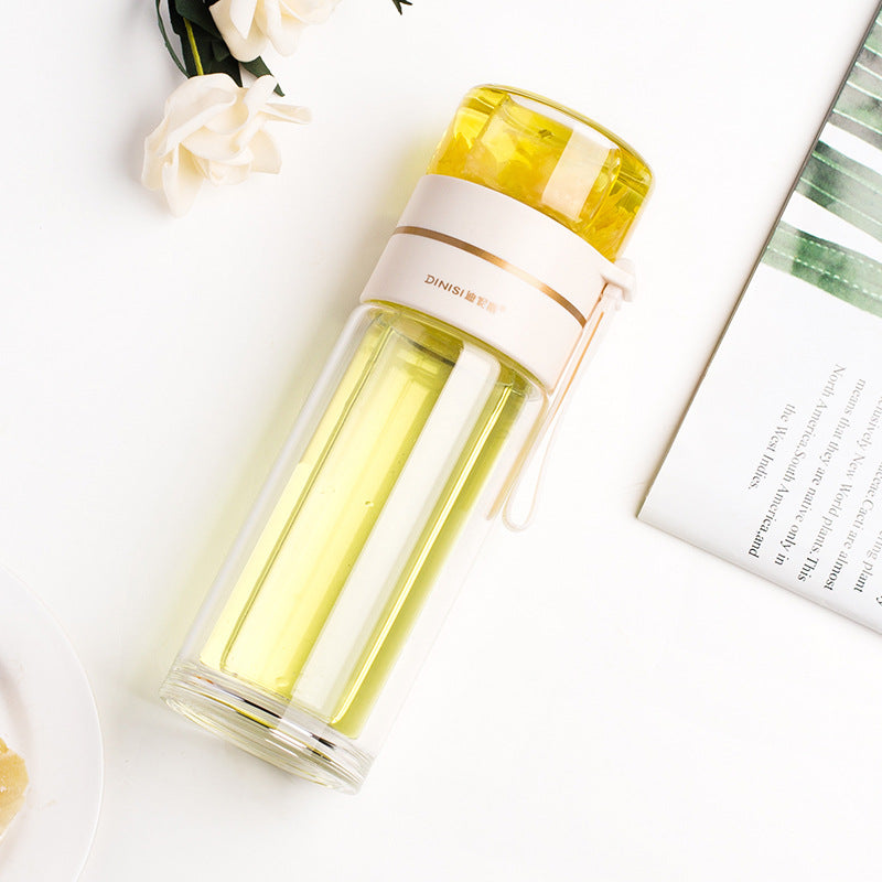 Clear water bottle with yellow top on a white surface with flowers and a magazine.