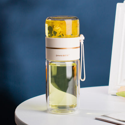 Clear glass water bottle with a white lid and handle, filled with a yellow liquid, on a white surface with a blue background.