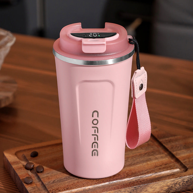 Pink coffee tumbler with digital display on a wooden surface
