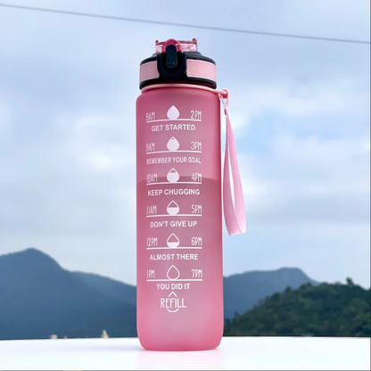 Pink water bottle with motivational text against a mountainous background