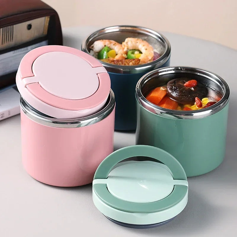 Three insulated food containers with pink, blue, and green lids on a light surface.