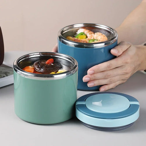 Two insulated food containers, one blue and one green, with food inside on a light surface.