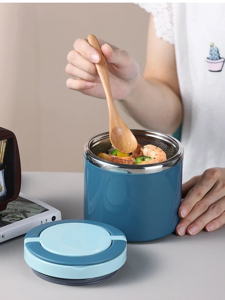 Person holding a wooden spoon over a blue thermos filled with food on a light surface.