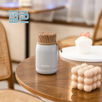 White thermos with wooden lid on a wooden table in a blurred indoor setting