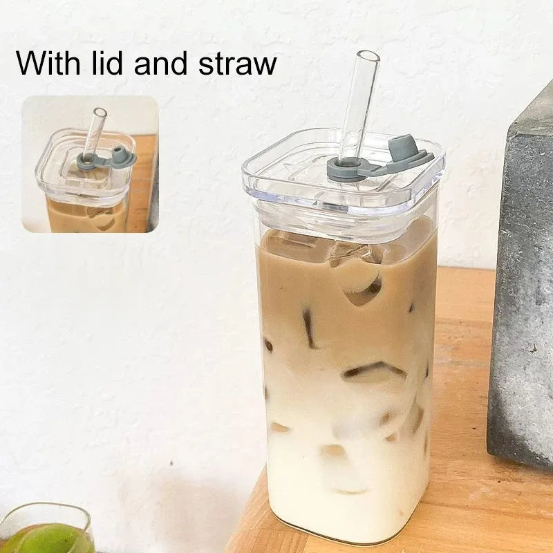 Clear tumbler with a lid and straw filled with iced coffee on a wooden surface.