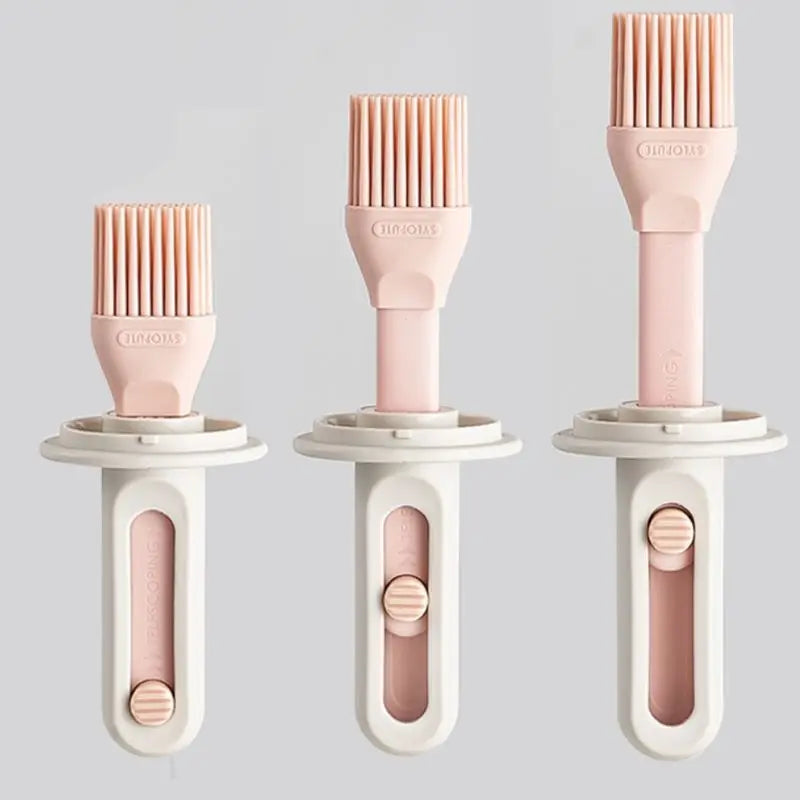 Three silicone basting brushes with pink bristles and beige handles on a light gray background.