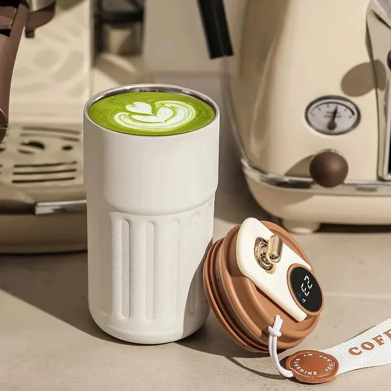 White ceramic tumbler with green beverage and brown lid on a vintage-style kitchen counter.