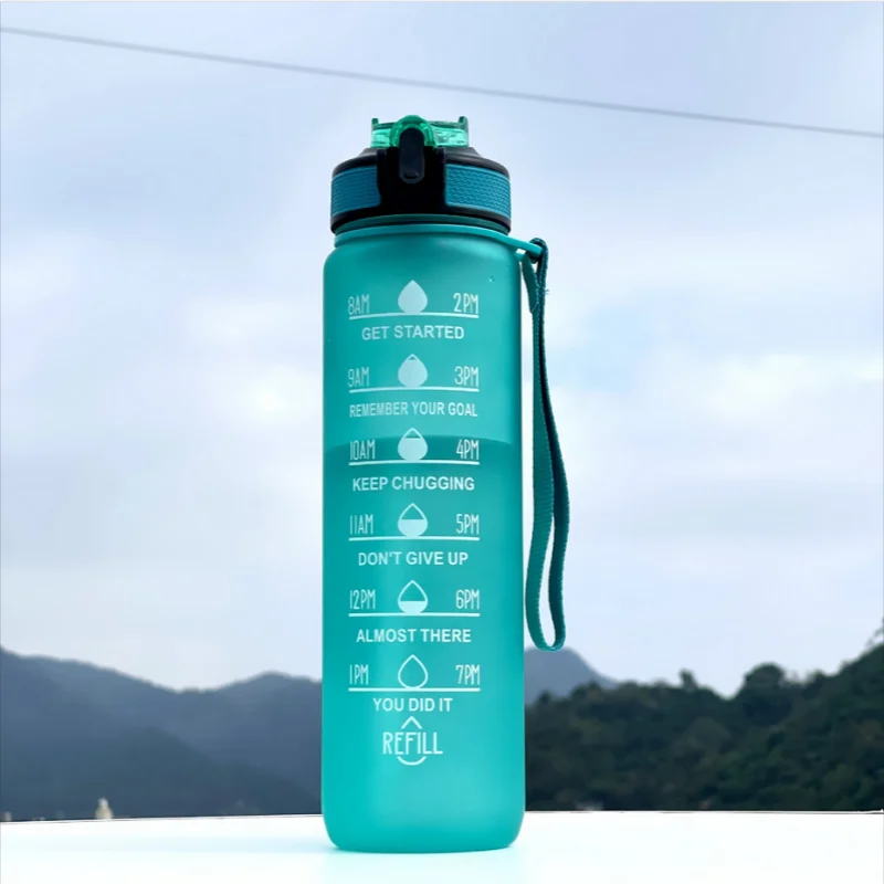 Teal water bottle with motivational markings against a mountainous background