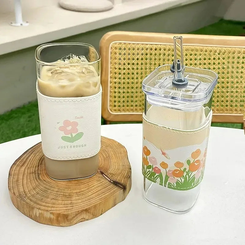 Two glasses with floral designs on a wooden coaster and table.
