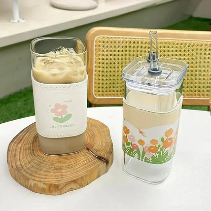 Two glasses with floral designs on a wooden coaster and table.