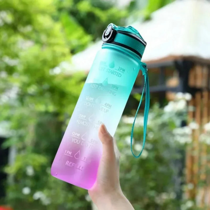 Gradient blue to pink water bottle with time markers held by a hand outdoors.