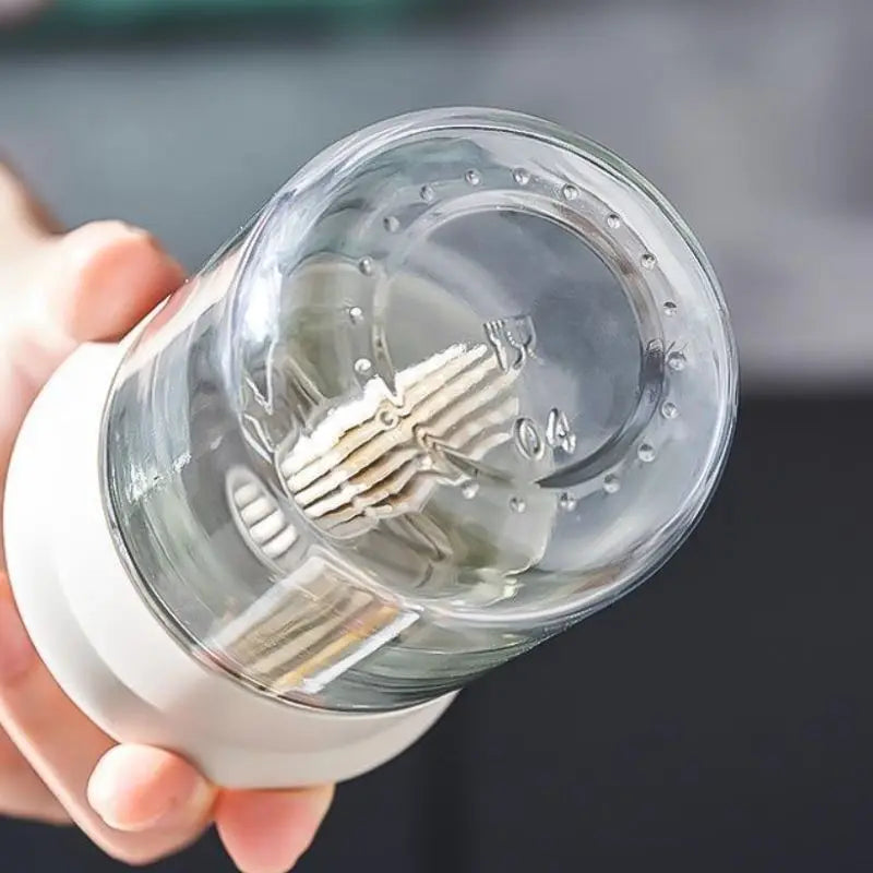 Clear light bulb with visible filaments held by a hand against a blurred background