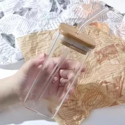 Clear glass container with wooden lid held by a hand on a textured surface