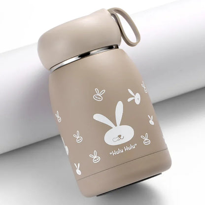 Beige thermos bottle with white rabbit illustrations on a light gray background