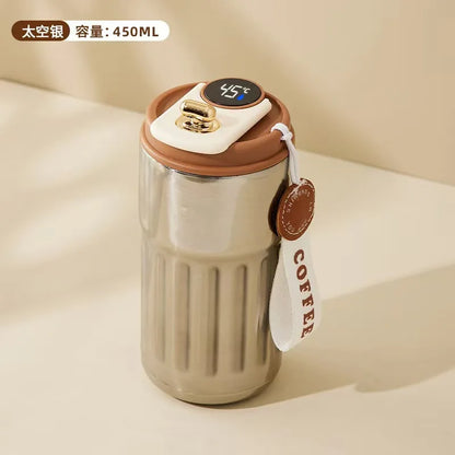 Stainless steel tumbler with brown lid and digital temperature display on a beige background