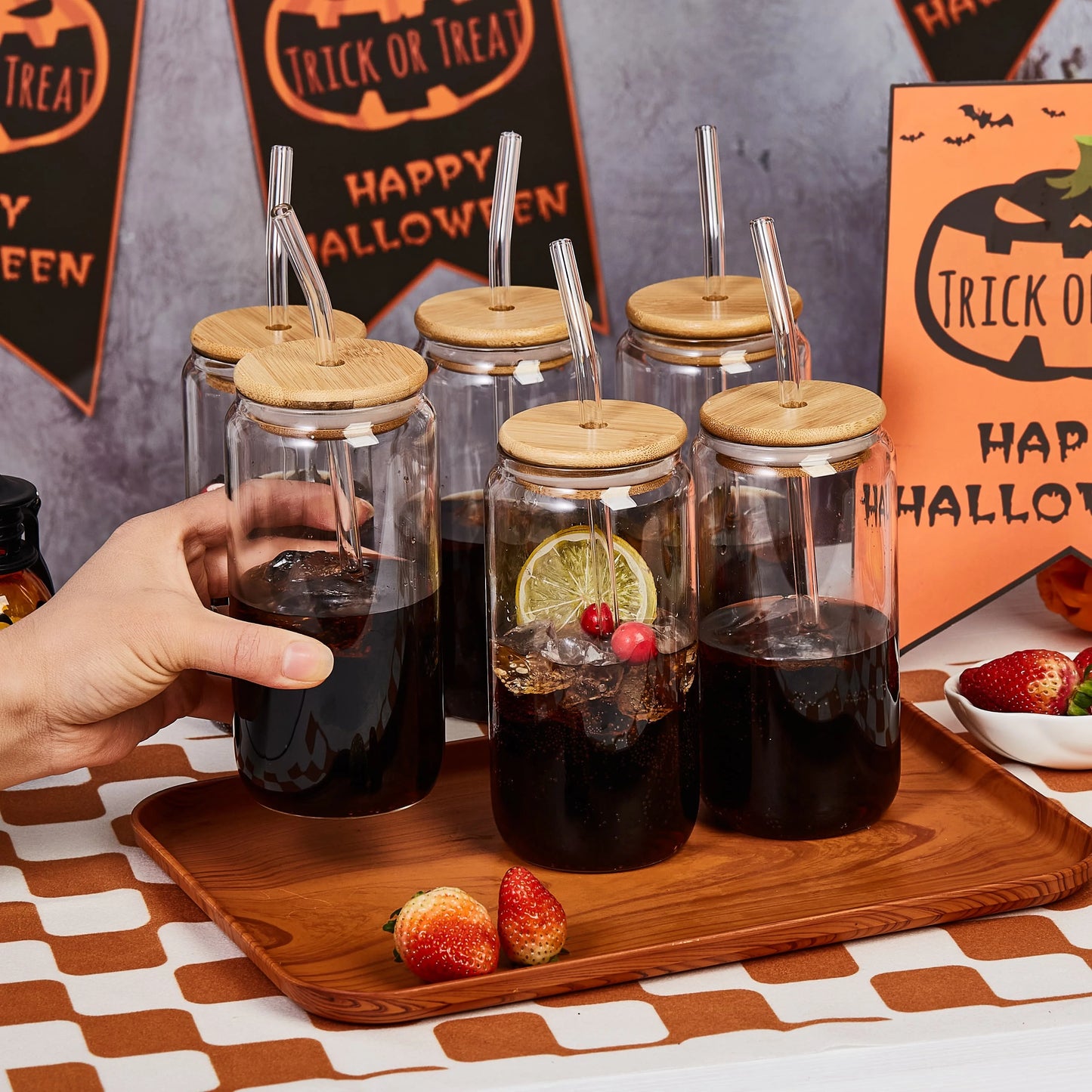 Set of glass jars with wooden lids and straws on a Halloween-themed table.