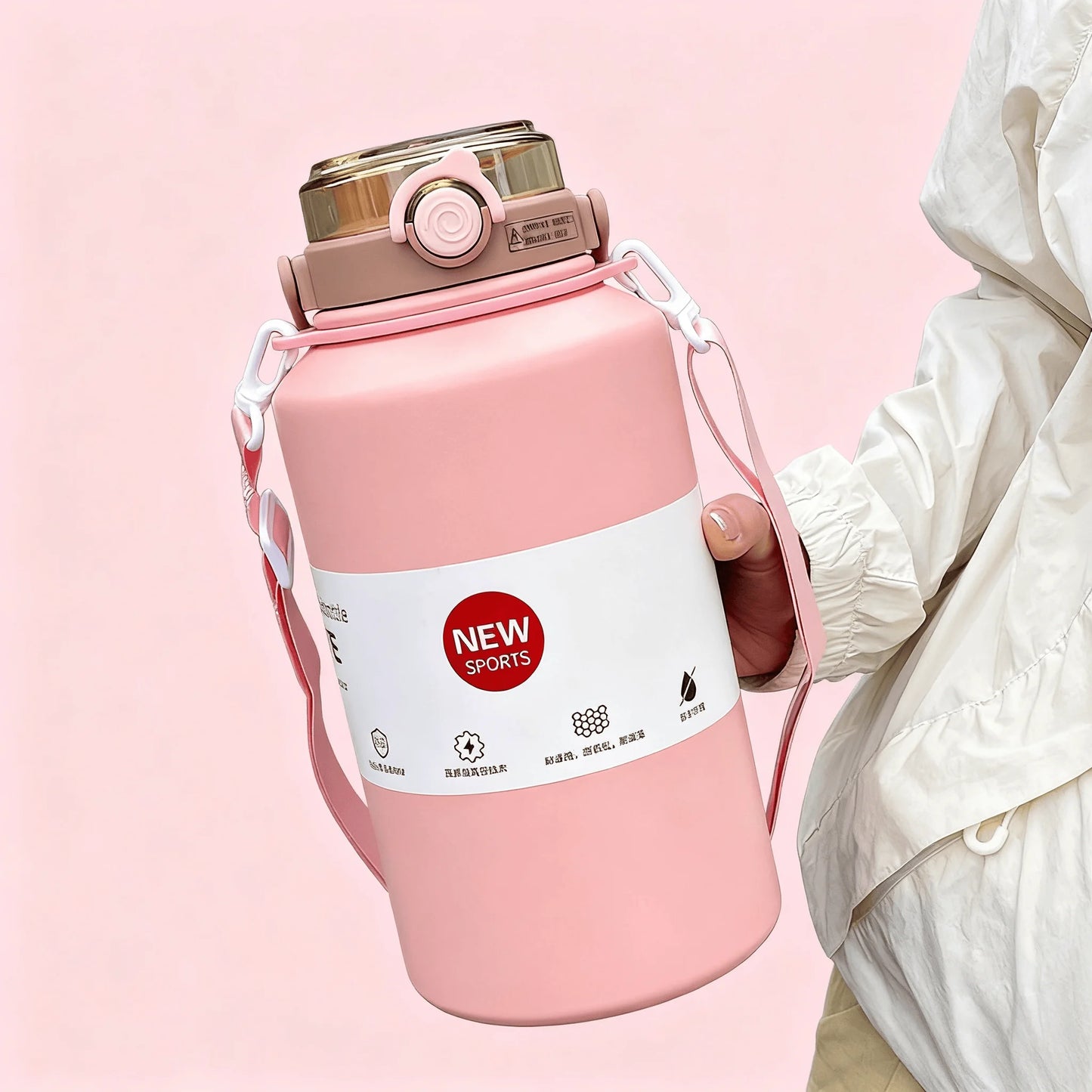 Pink water bottle with a strap held by a person on a pink background
