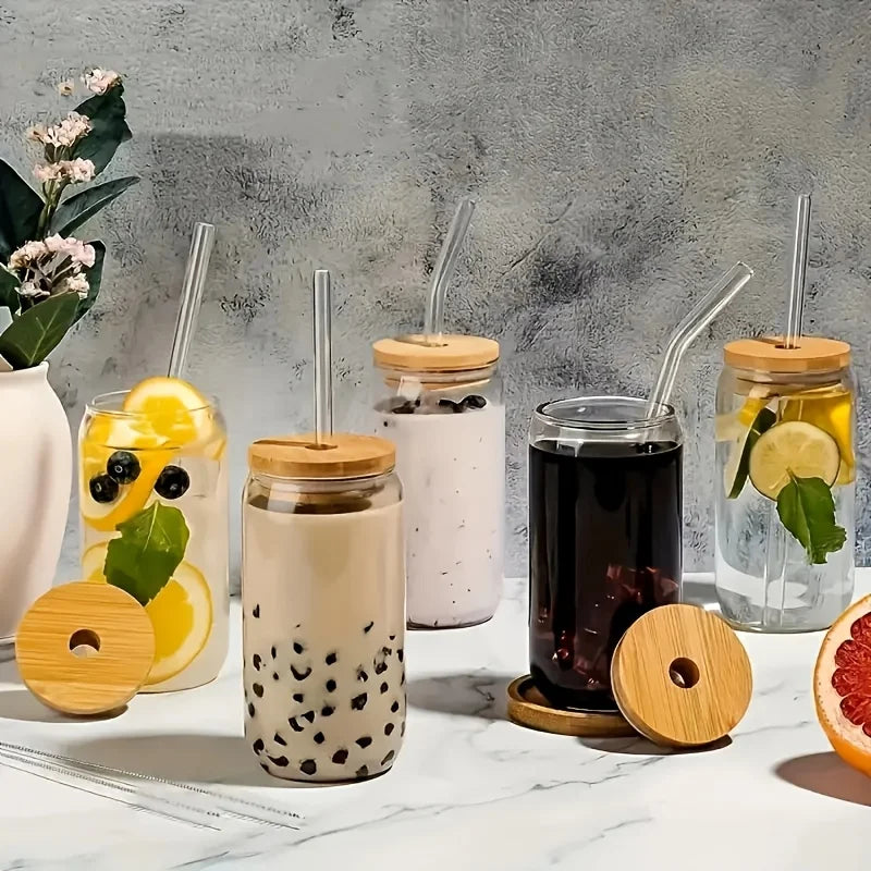 Collection of glass drinks with wooden lids and straws on a marble surface.