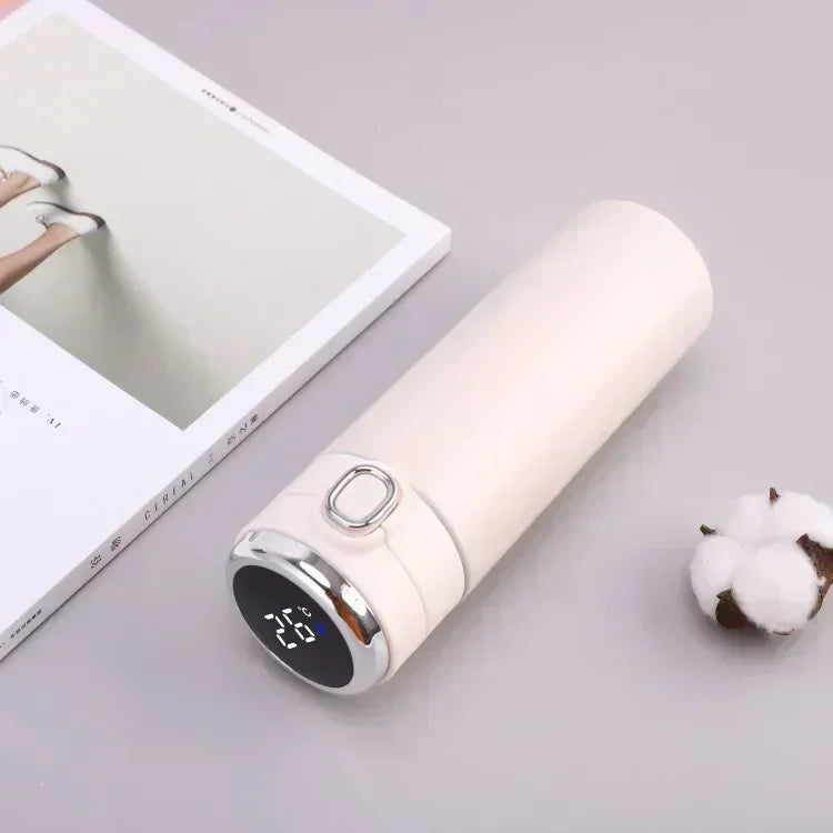 White power bank with digital display on a light gray surface with a book and cotton ball.